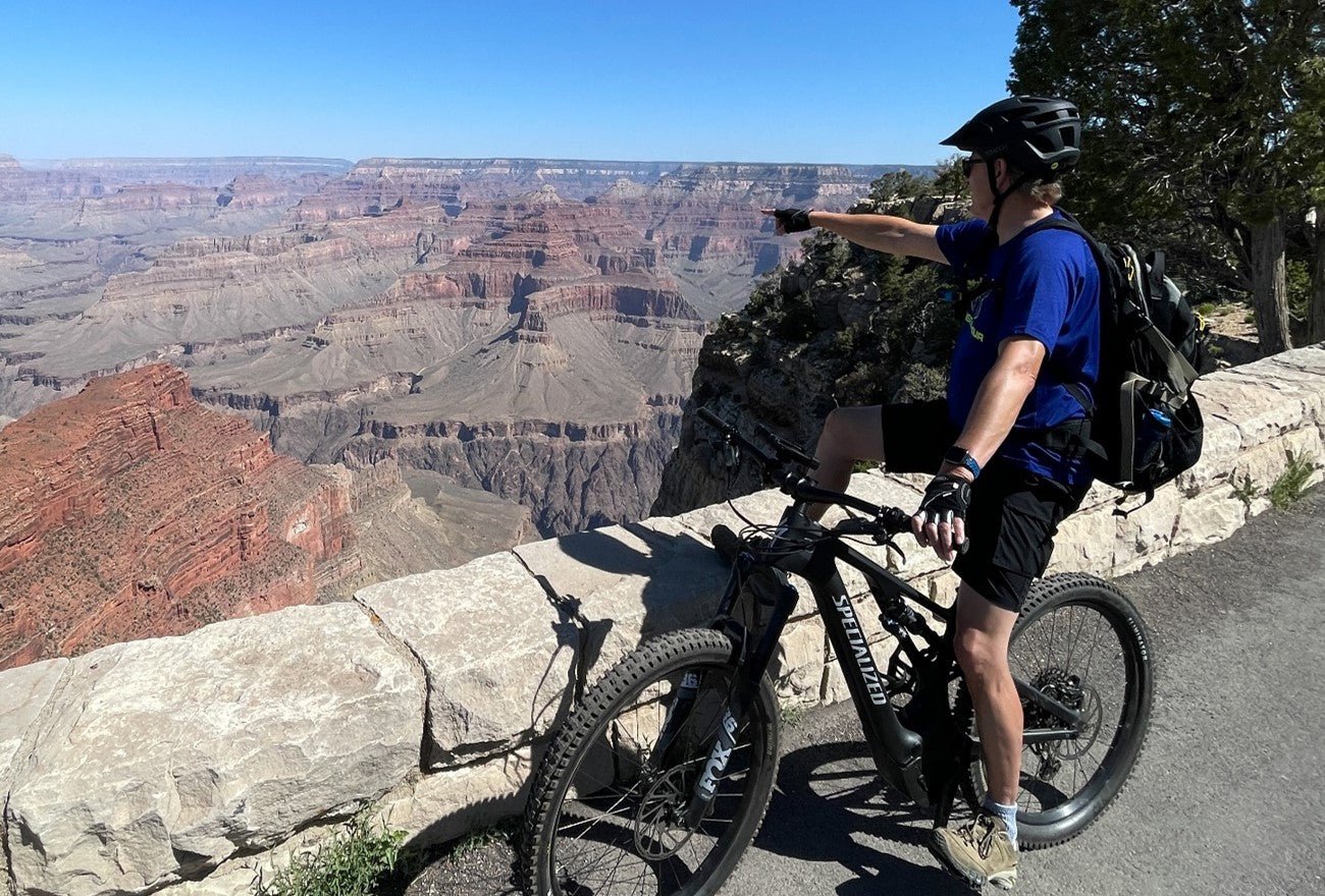 Man pointing at Grand Canyon on his E-Bike.