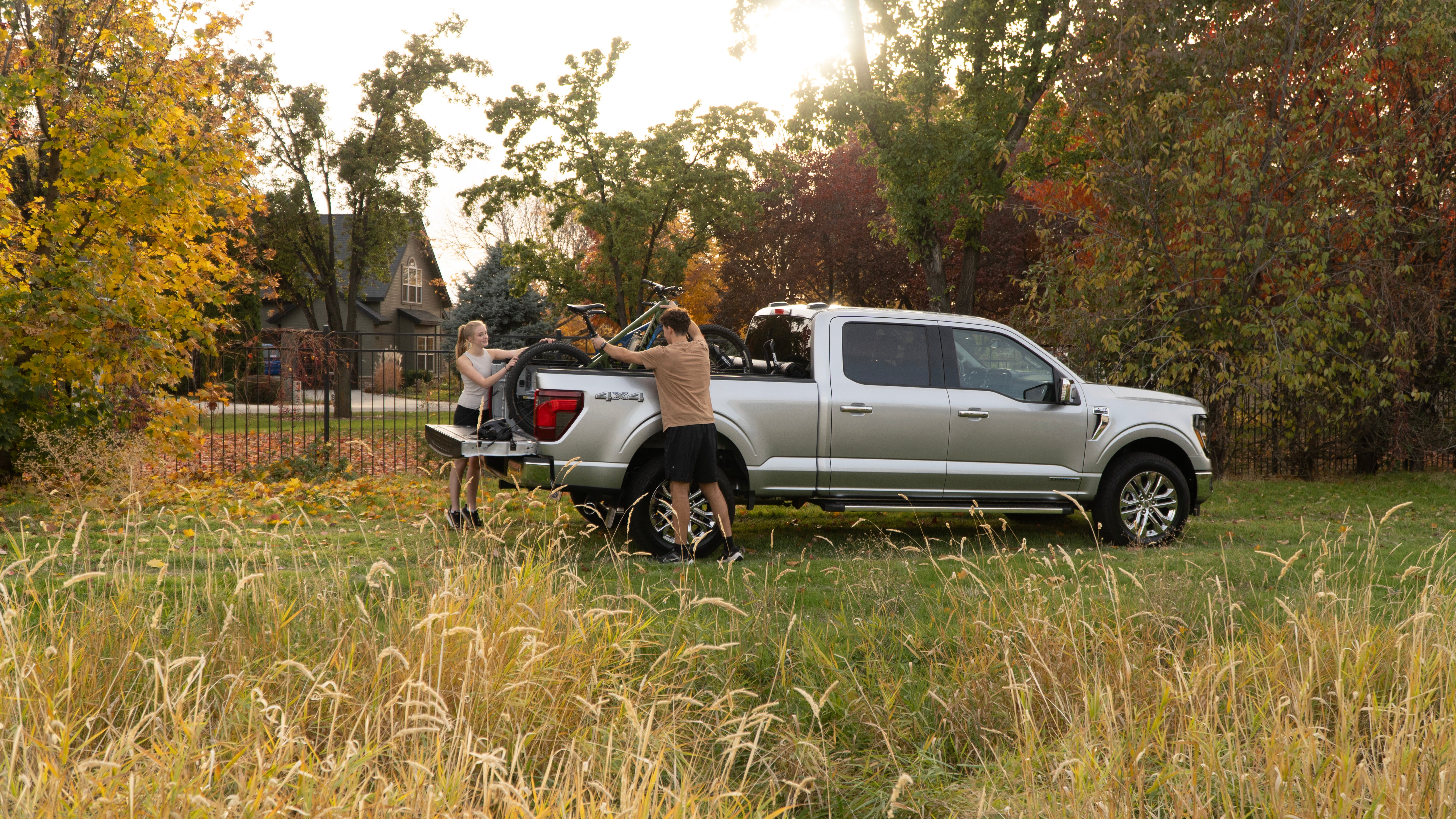 Two people are removing bikes from a truck bed, demonstrating the RIDE88 QR3 bike carrier.