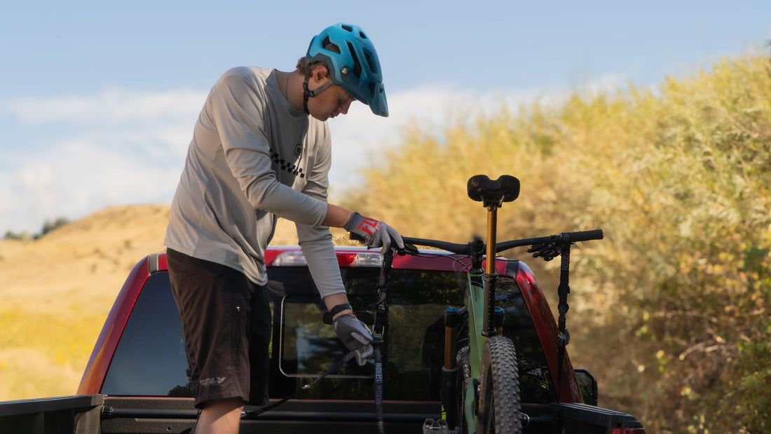 Person loading a bicycle into the back of a pickup truck using the RIDE88 Cinch Rack for truck beds.