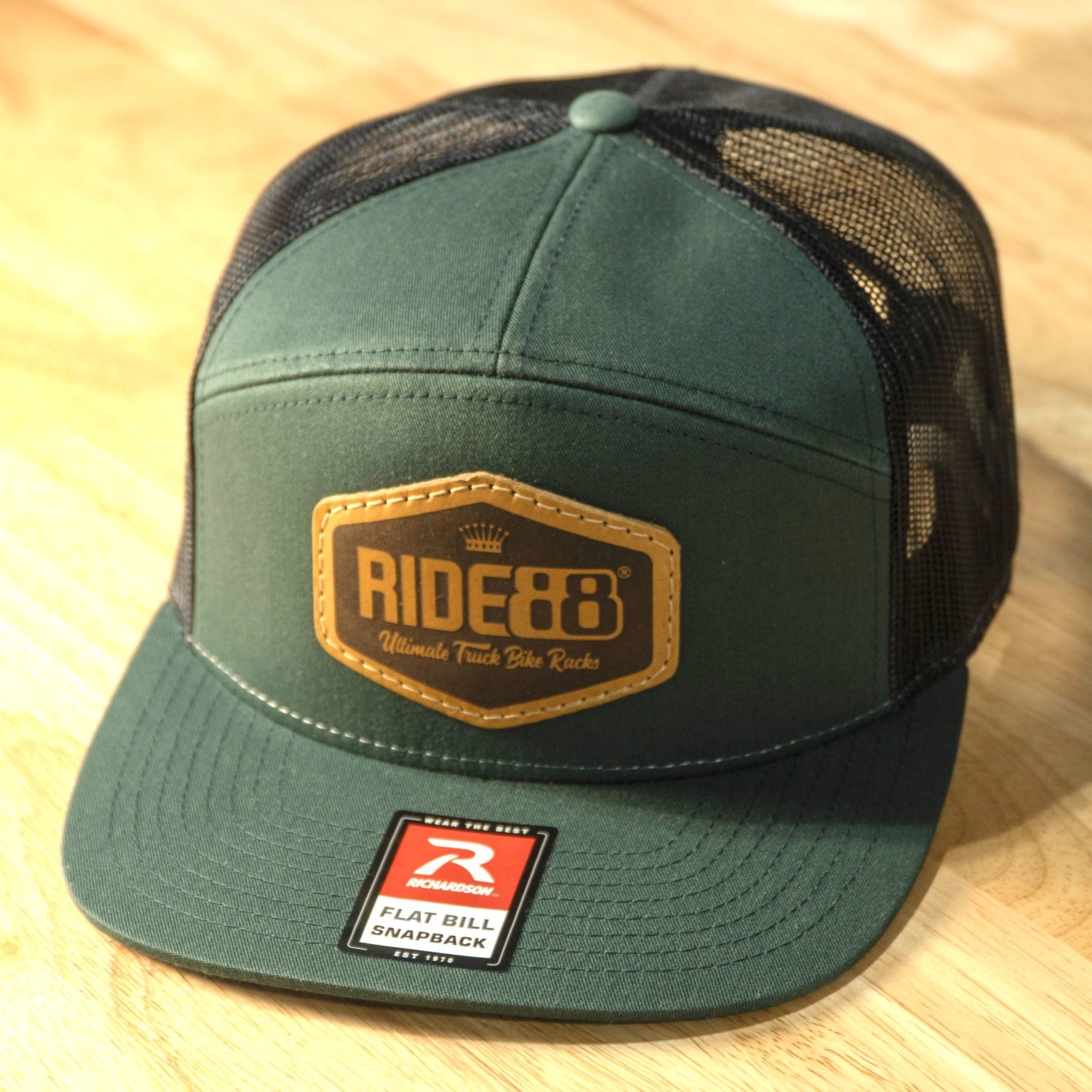 RIDE88 green and black trucker hat with brown leather patch logo reading “RIDE88 Ultimate Truck Bike Racks,” featuring flat bill and mesh back design.