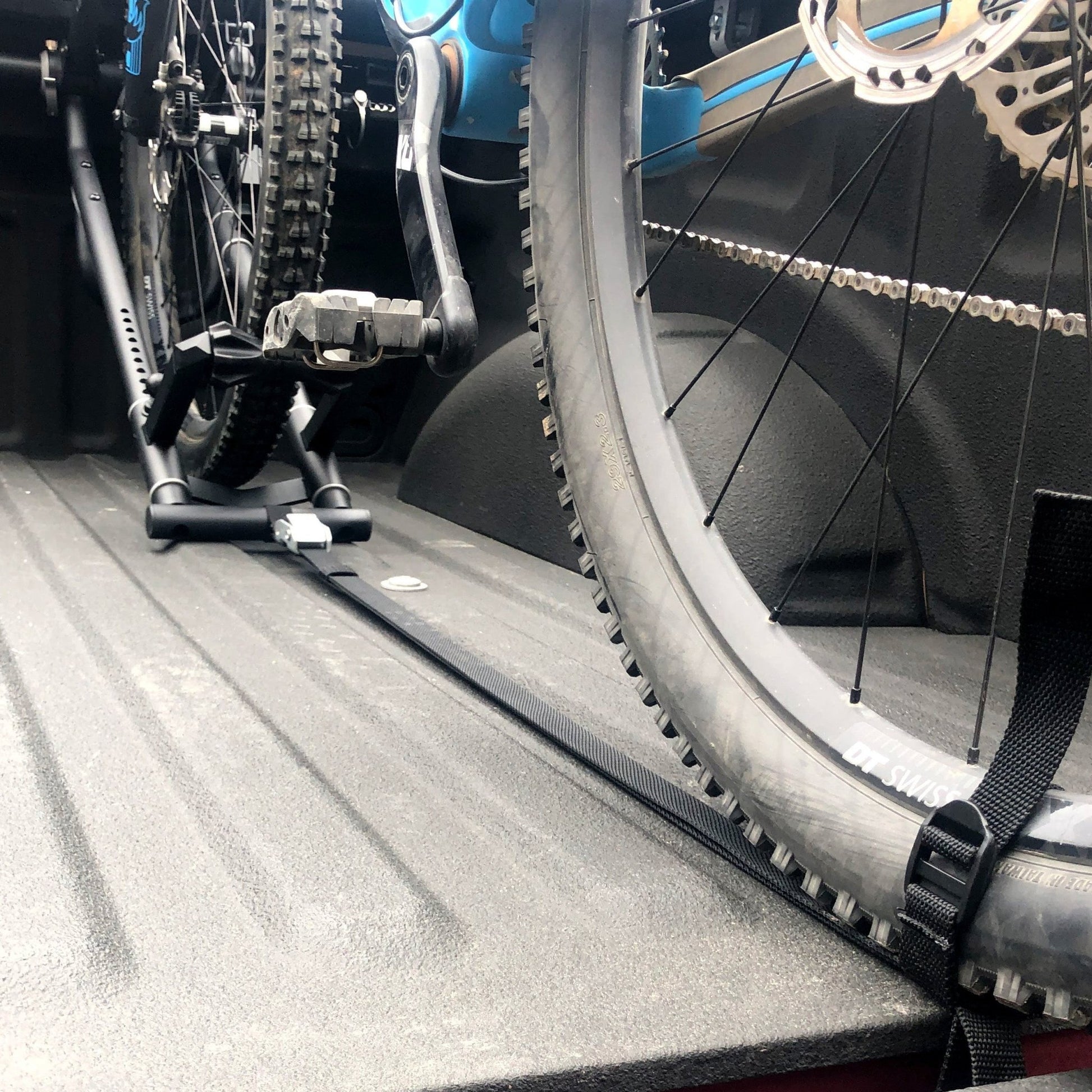 RIDE88 QR3 bike rack rear tire strap securing the back wheel of a mountain bike in a truck bed.