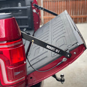 Two RIDE88 Tailgate Boss Pro-Kit truck bed support bars mounted on a red pickup/ holding the bed at a slight angle and keeping it from bouncing.