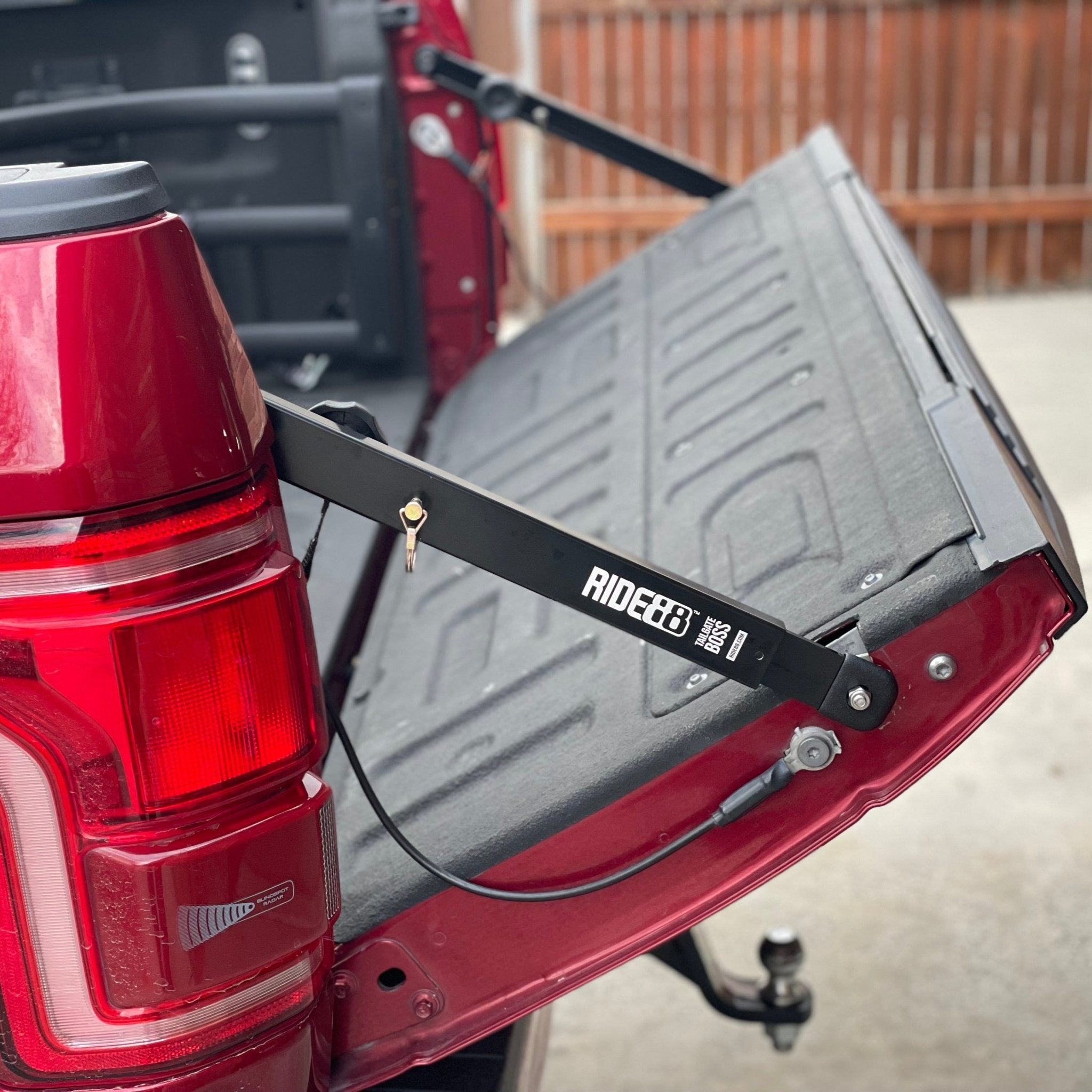 Two RIDE88 Tailgate Boss Pro-Kit truck bed support bars mounted on a red pickup/ holding the bed at a slight angle and keeping it from bouncing.