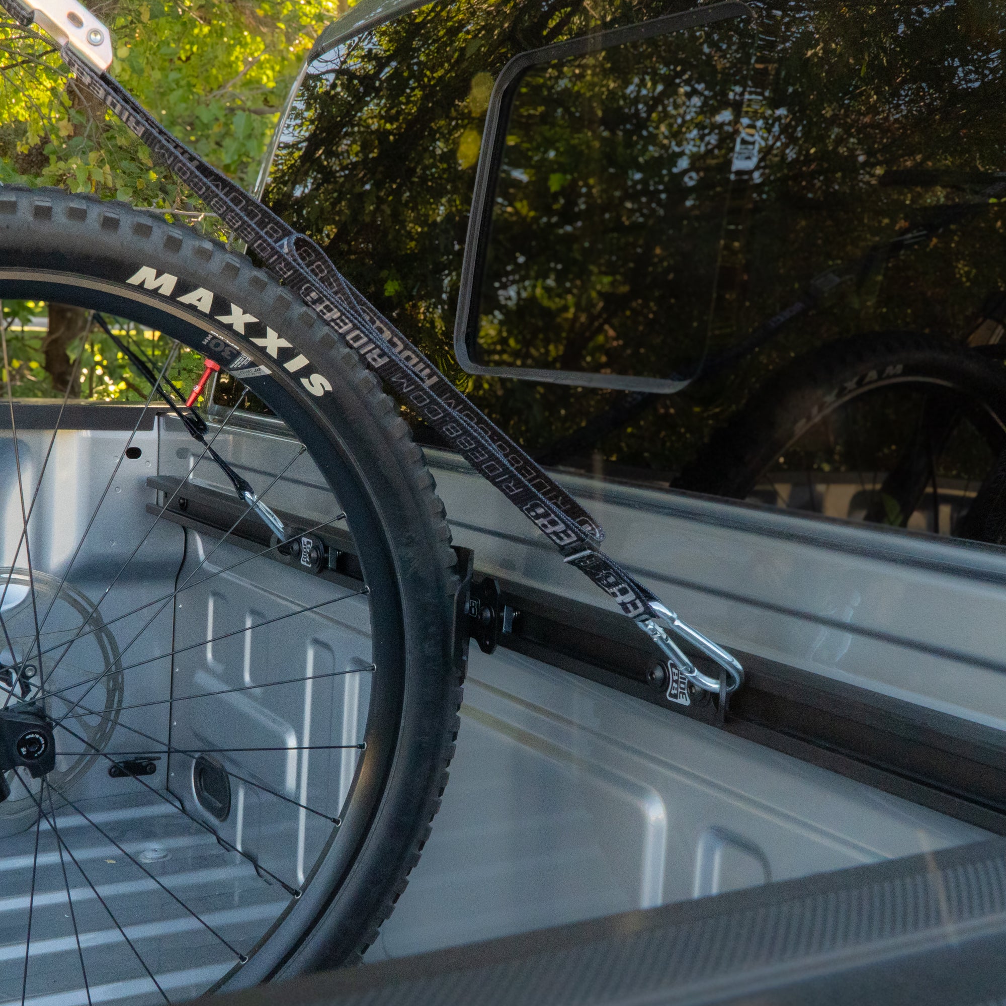 Bike secured in a pickup truck bed using the RIDE88 U-Track Plus One Kit, showing a mountain bike mounted to a truck bed rail system.