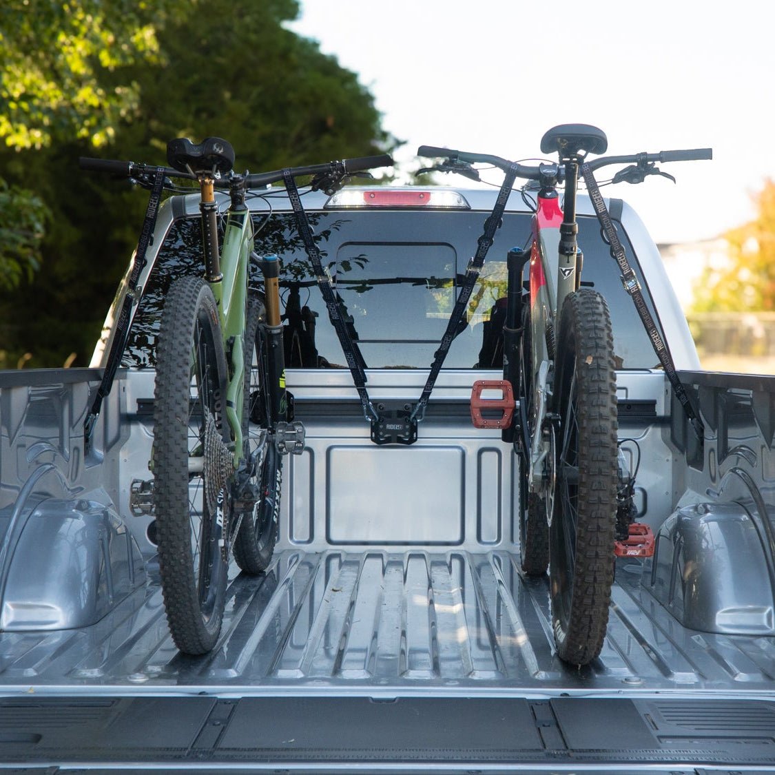 Two bikes mounted in a pickup truck bed with RIDE88 Cinch truck bed rail mounted bike racks.